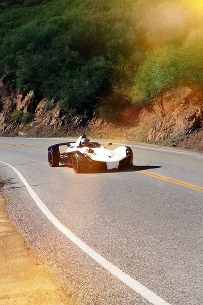 White modern sport car is driving on empty countryside asphalt road at sunset - 写真・画像
