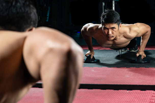 Los asiáticos se ejercitan empujando el suelo en el gimnasio moderno
. - Foto, Imagen