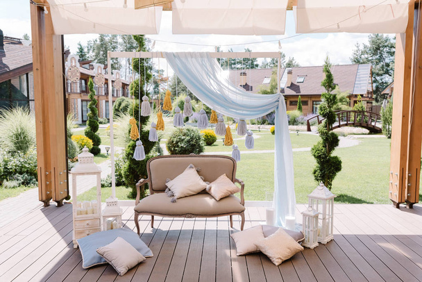 Un magnifique canapé beige, des oreillers gracieux et de jolis détails pour se reposer sur une terrasse
 - Photo, image