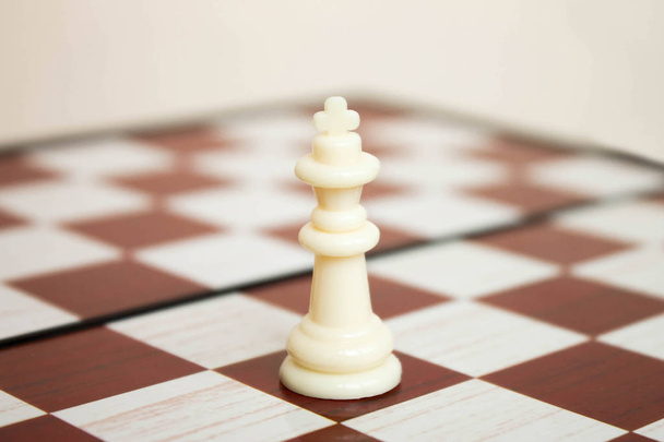 White plastic chesspiece the king on the chessboard closeup - Fotó, kép