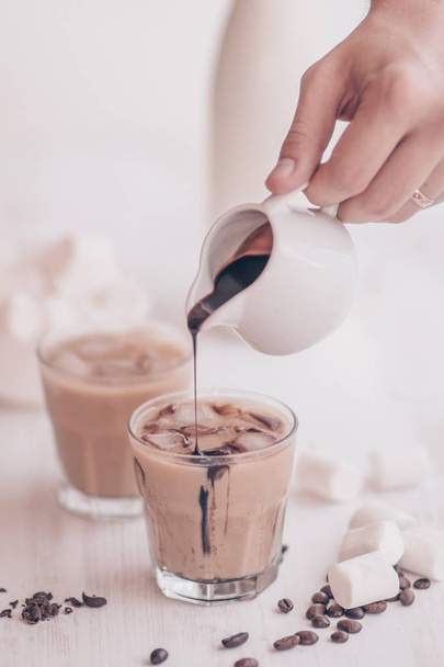 Concept of a cooling drink. Marshmelow and coffee beans on the table. Summer drink. Cold coffee with milk and chocolate. Light background. Iced coffee. - Foto, Imagen