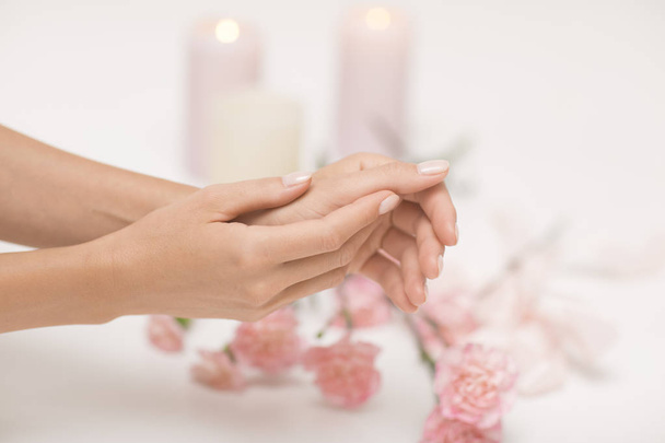 Манікюр. Красиві і ніжні руки на білому тлі з рожевими квітами
. - Фото, зображення
