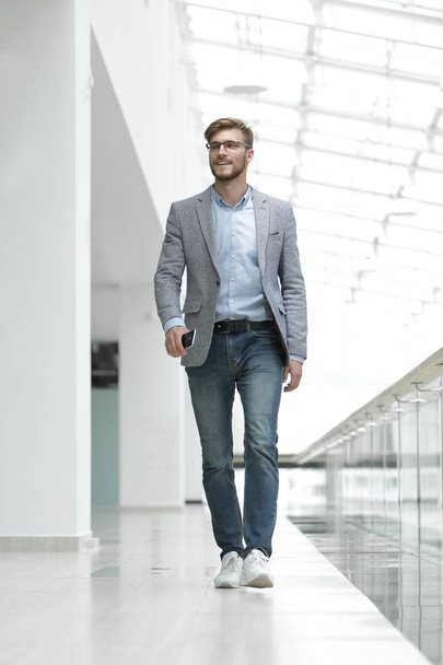 confident business man walks through a bright office - Fotoğraf, Görsel