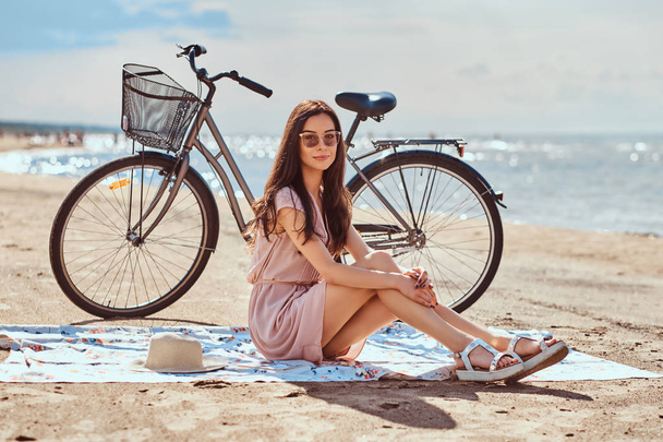 Ευτυχισμένος νεαρή γυναίκα σε γυαλιά ηλίου και φόρεμα Απολαύστε διακοπές στην παραλία. - Φωτογραφία, εικόνα