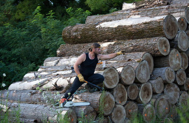 A láncfűrész és hegymászás, fából készült gerendák halom ax fiatal erős Favágó - Fotó, kép