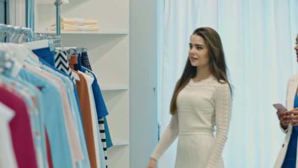 Jóvenes mujeres felices comprando ropa en la tienda
 - Imágenes, Vídeo