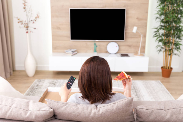 alleinstehende Frau isst Pizza und schaut fern - Foto, Bild