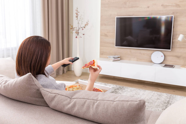 Mulher solteira comendo pizza e assistindo tv
 - Foto, Imagem