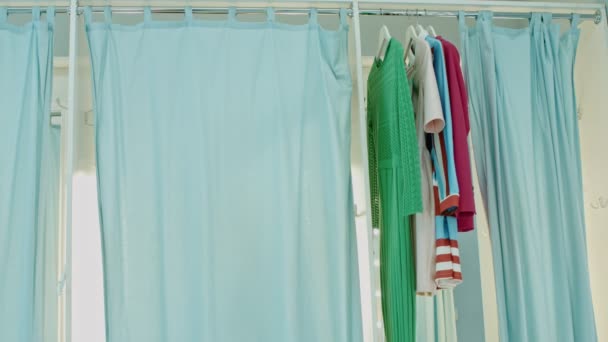 Nuori nainen kokeilee vaatteita myymälän sovitushuoneessa
  - Materiaali, video