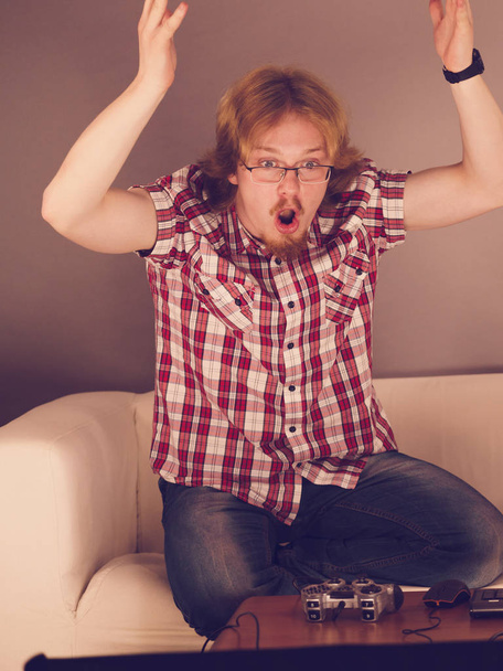 Nerd geek angry adult man playing on the video console holding game pad being mad and furious - Foto, Imagen