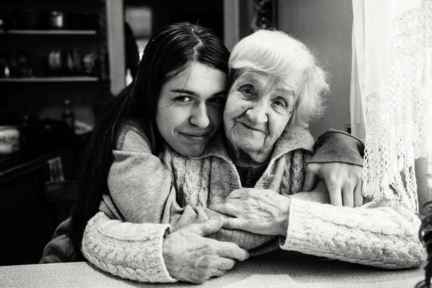 村の家で大人の孫娘と抱擁で年配の女性。黒と白の写真. - 写真・画像