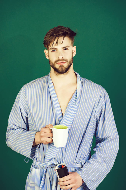 macho in blue robe holding cup and magazine - Foto, imagen