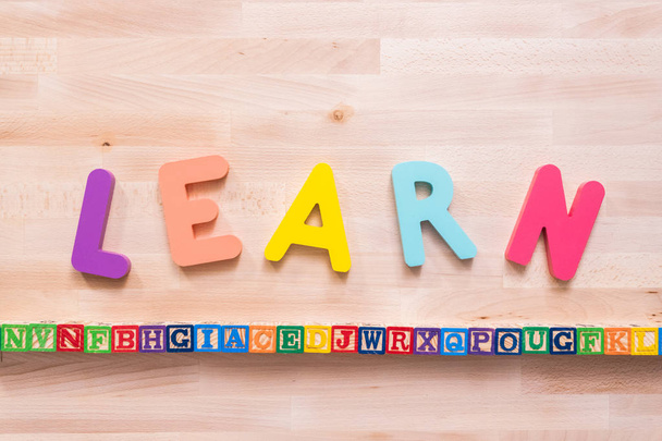Bright color wooden LEARN sign on wood desk. - Photo, Image