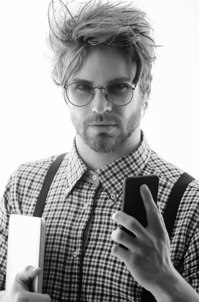 Handsome man or male student, businessman, with beard and stylish, blond hair, in nerd glasses with smartphone and laptop computer. Using technology, internet surfing and video conferencing - Foto, Bild