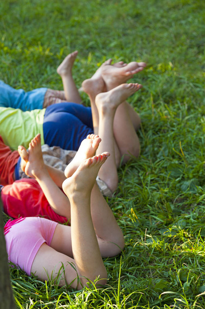 Happy children lying on green grass outdoors in spring park - Fotografie, Obrázek