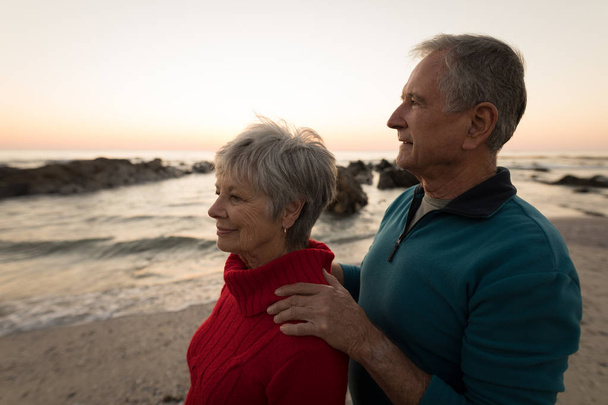 Close-up van senior paar staande op strand tijdens zonsondergang - Foto, afbeelding