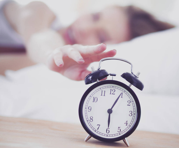 Young sleeping woman and alarm clock in bedroom at home. Young sleeping woman. - Φωτογραφία, εικόνα