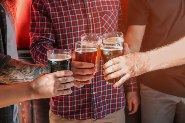 Ομάδα φίλων που τσούγκριζαν τα ποτήρια με μπίρα σε χρώμα φόντου - Φωτογραφία, εικόνα