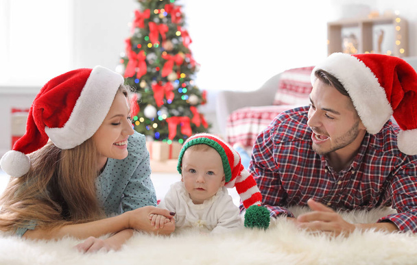Happy couple with baby in Christmas hats at home - Photo, image