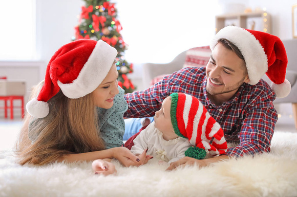 Happy couple with baby in Christmas hats at home - Фото, зображення