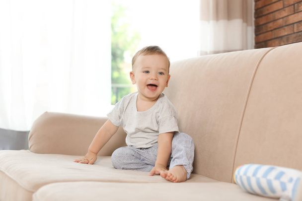 Adorable little baby sitting on sofa at home - Zdjęcie, obraz