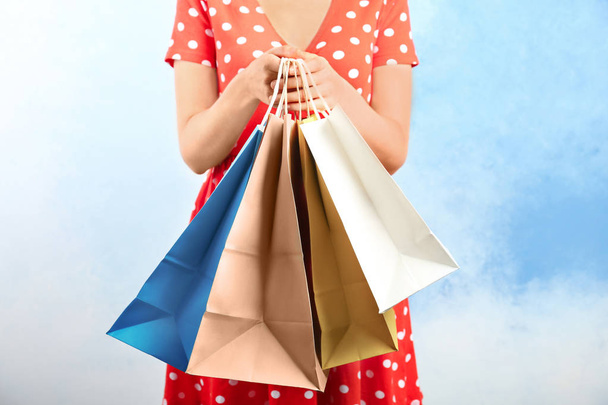 Woman holding paper shopping bags on color background - Zdjęcie, obraz