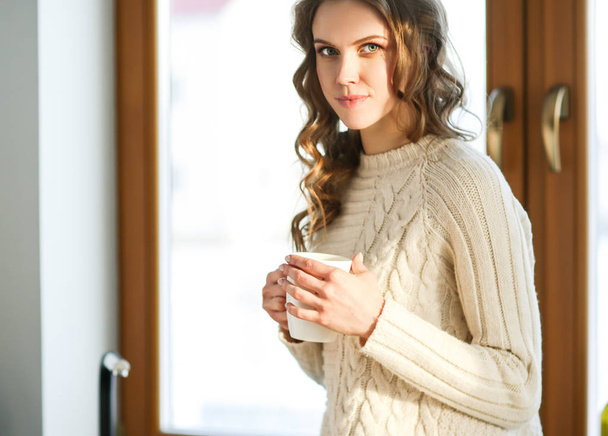 Portrait d'une femme tenant une tasse de thé dans sa cuisine
. - Photo, image