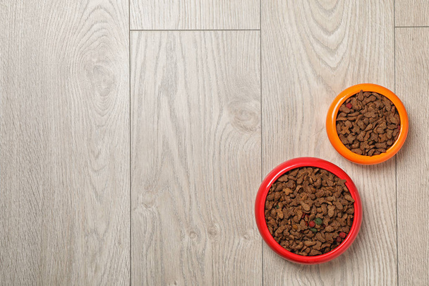 Bowls with food for cat and dog on wooden background. Pet care - Fotoğraf, Görsel