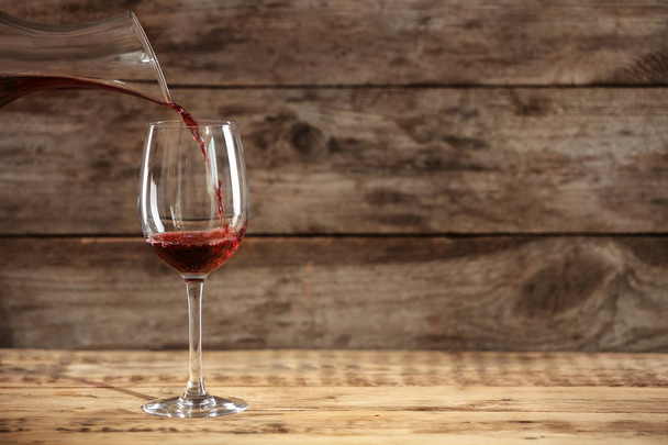 Gieten van heerlijke rode wijn in glazen op tafel - Foto, afbeelding