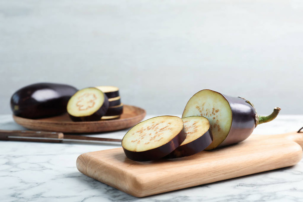 Wooden board with ripe eggplants on table - Фото, зображення
