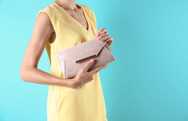 Young woman in stylish outfit with purse on color background, closeup - Foto, Imagem