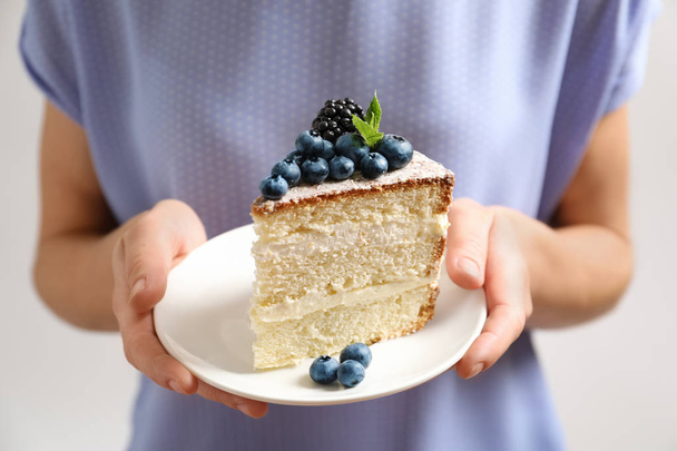 Woman holding piece of delicious homemade cake with fresh berries on plate, closeup - Фото, изображение