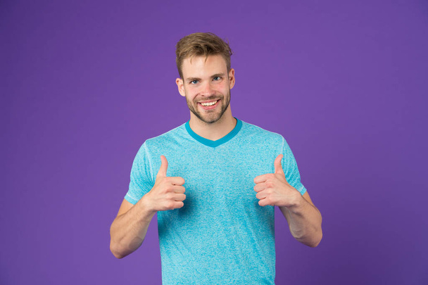 Approve or recommend concept. Man with brilliant smile unshaven face shows thumbs up gesture violet background. Man happy cheerful face support or recommend. Guy happy emotional approve expression - Photo, Image