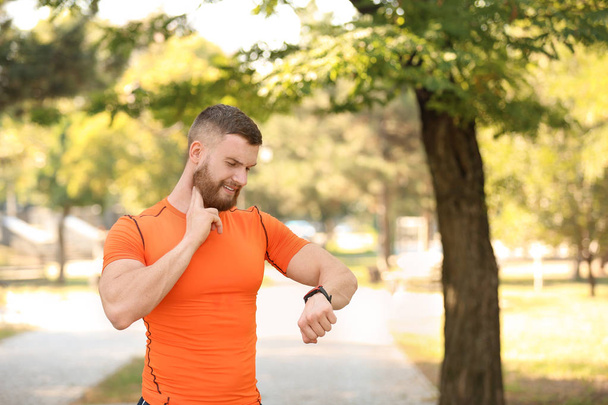 Young man checking pulse after workout in park - Foto, imagen