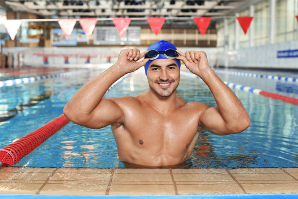 Kap ve gözlük yüzme havuzunda giyen genç atletik adam - Fotoğraf, Görsel