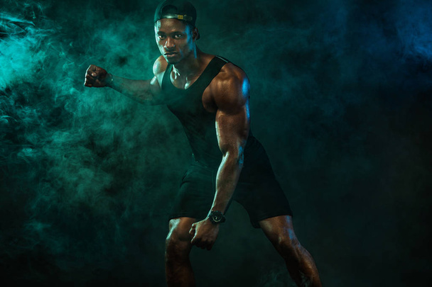 Sports wallpaper on dark background. Power athletic guy bodybuilder. Fire, smoke and energy. - Foto, afbeelding
