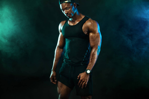 Sports wallpaper on dark background. Power athletic guy bodybuilder. Fire, smoke and energy. - Photo, image