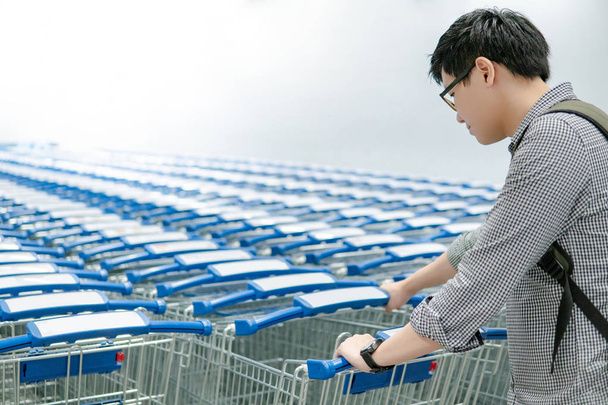 スーパー マーケットや食料品店の行からショッピング カート (トロリー) を引いて買い物客はアジア系の若い男します。ショッピング ライフ スタイル コンセプト - 写真・画像