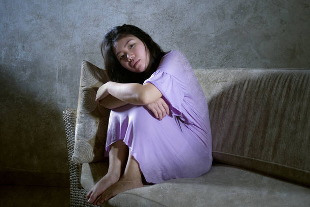young sad and depressed Asian Chinese woman crying alone desperate and worried in pain suffering depression and anxiety problem feeling lonely at home sofa couch in dramatic light - Foto, Bild