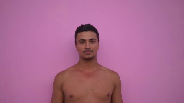 Young handsome hispanic man portrait with naked torso and moustache on pink background looking serious pensive at camera close up. Vitiligo on skin. - Footage, Video