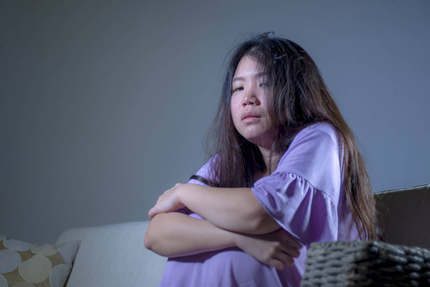 young sad and depressed Asian Chinese woman at home sofa couch crying desperate and helpless suffering anxiety and depression feeling pain in relationship and lonely life problem concept - Valokuva, kuva