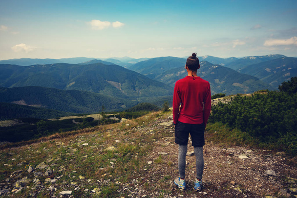 Dobrodruh, chlap teenagera stojí v horách, obdivuje výhledem na zelené horské hřbety, táhnoucí se do blue horizon. Epické cestování přes poušť. Pohled zezadu.  - Fotografie, Obrázek