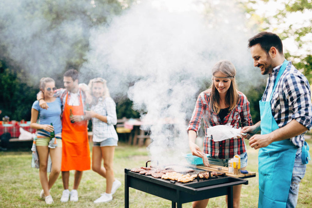 Happy friends enjoying barbecue party outdoors - Fotó, kép