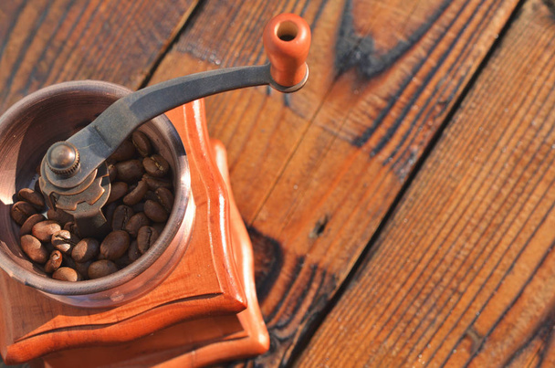 The manual horizontal coffee grinder with coffee beans on wooden boards is in the lower left corner. - Foto, Imagen