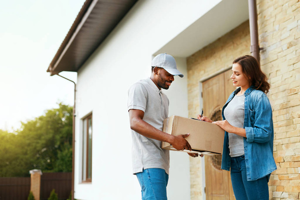 Package Delivery. Man Courier Delivering Box To Woman At Home - Foto, imagen