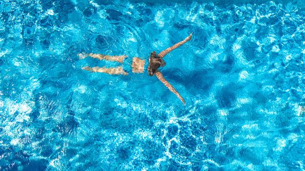 Aerial drone view of active woman in swimming pool from above, girl swims in blue water, tropical vacation, holiday on resort concept - Фото, зображення