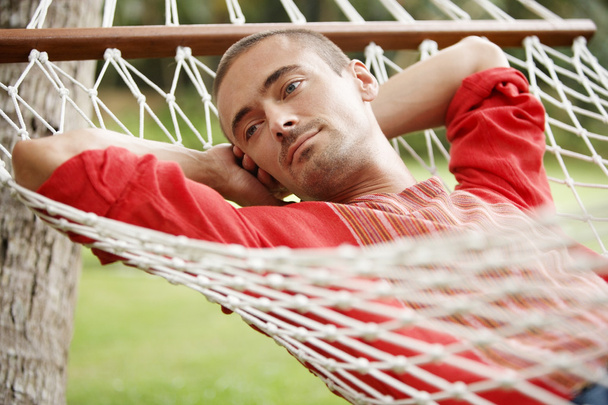 attractive young man laying down on a hammock - Фото, зображення