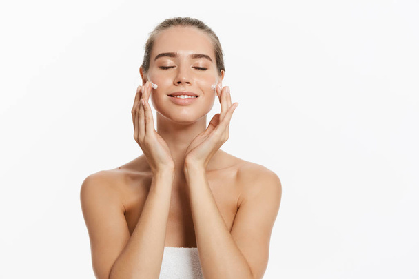 Красива молода жінка застосовує косметичне лікування крему на обличчі ізольовано на білому тлі
 - Фото, зображення