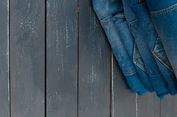 jeans stacked on wooden background, close-up  - Valokuva, kuva