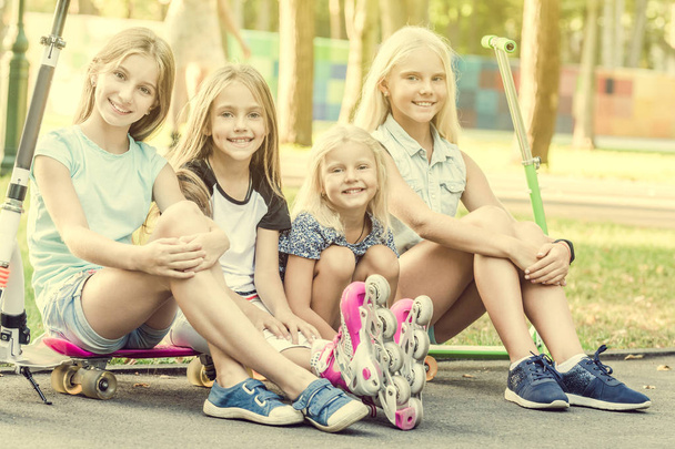 Smiling little girls sitting on the ground in the park - Foto, imagen